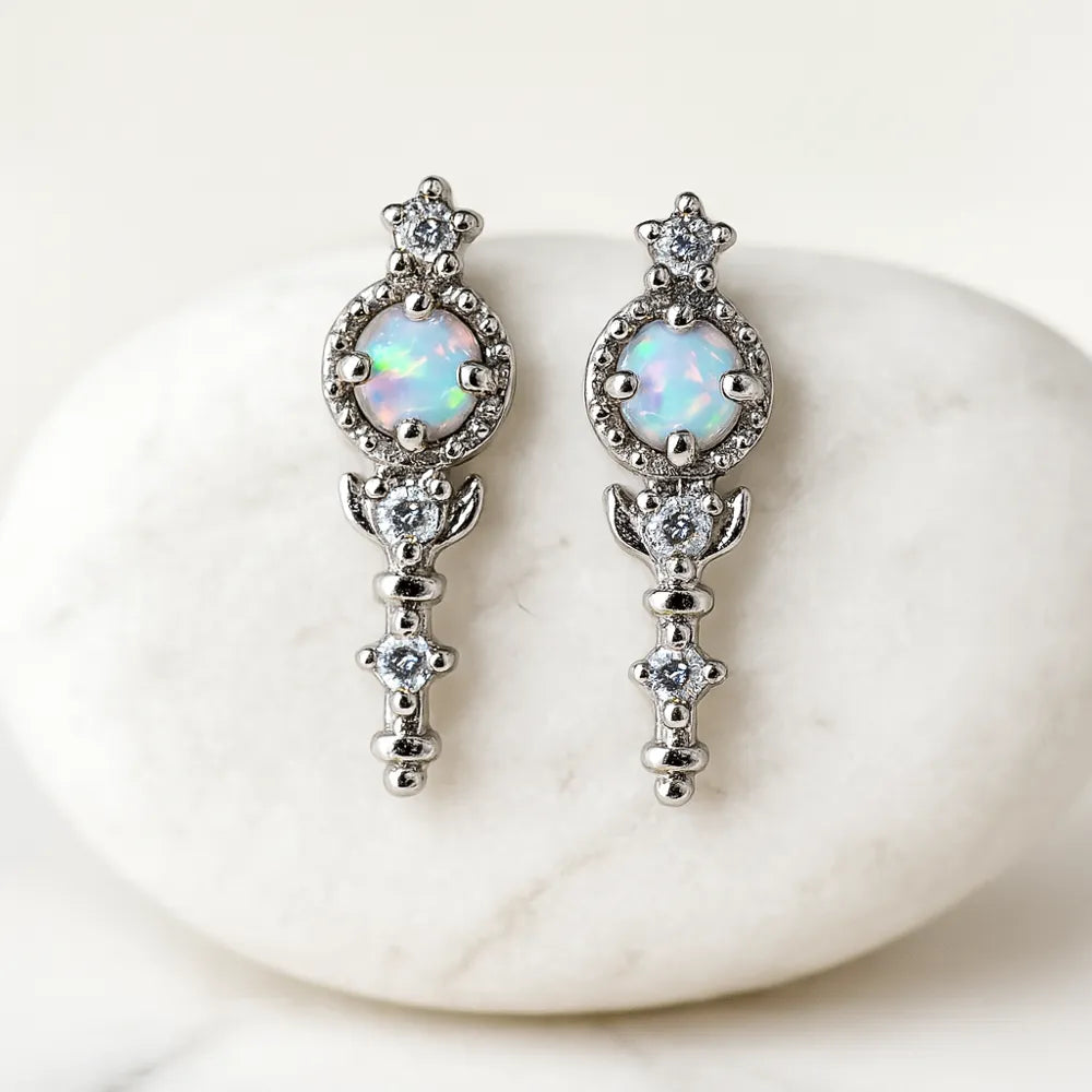 Pair of silver earrings with opal stones on a white stone background