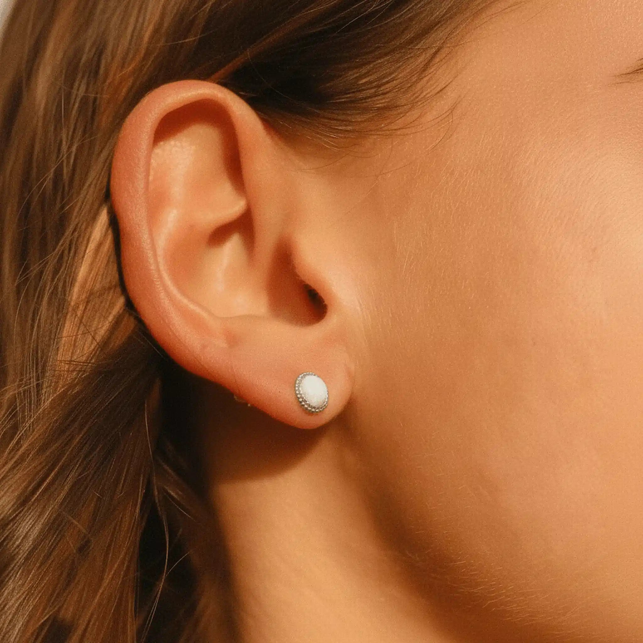 Close-up of an ear wearing a silver stud white opal earring