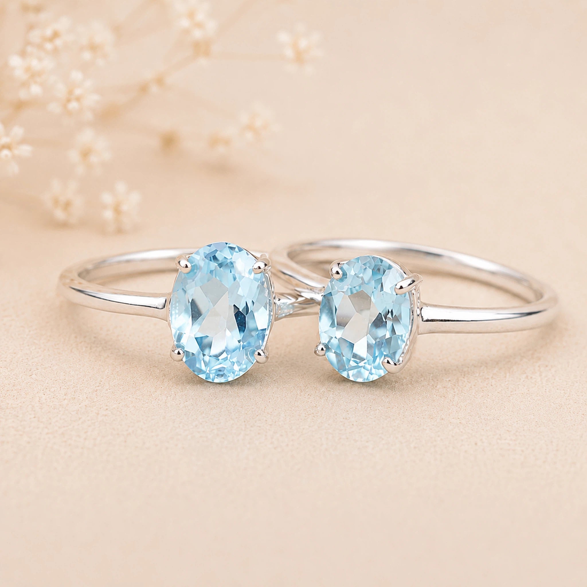 sterling silver rings with a oval shaped faceted claw set blue topaz gemstones on a light surface.