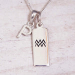 Sterling Silver P Initial and Aquarius Necklace on a fine silver chain against a light wooden background