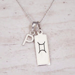 Sterling silver P initial and GeminI Necklace on a fine silver chain on a light wooden background