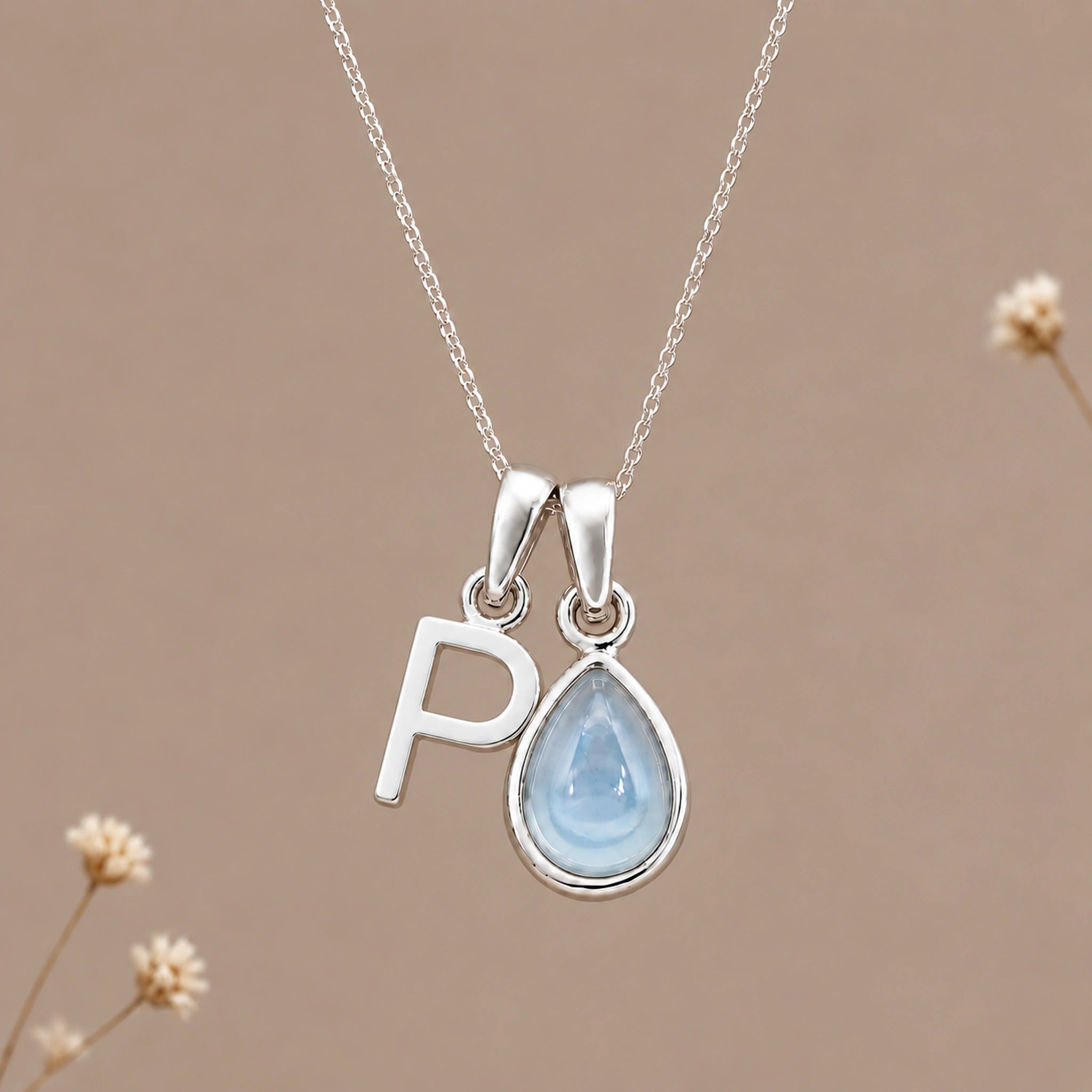 Sterling silver initial P and November natural blue topaz necklace on a taupe background with sparse ivory flowers
