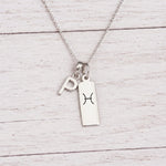 sterling silver P initial Pisces Necklace on a fine silver chain against a light wooden background
