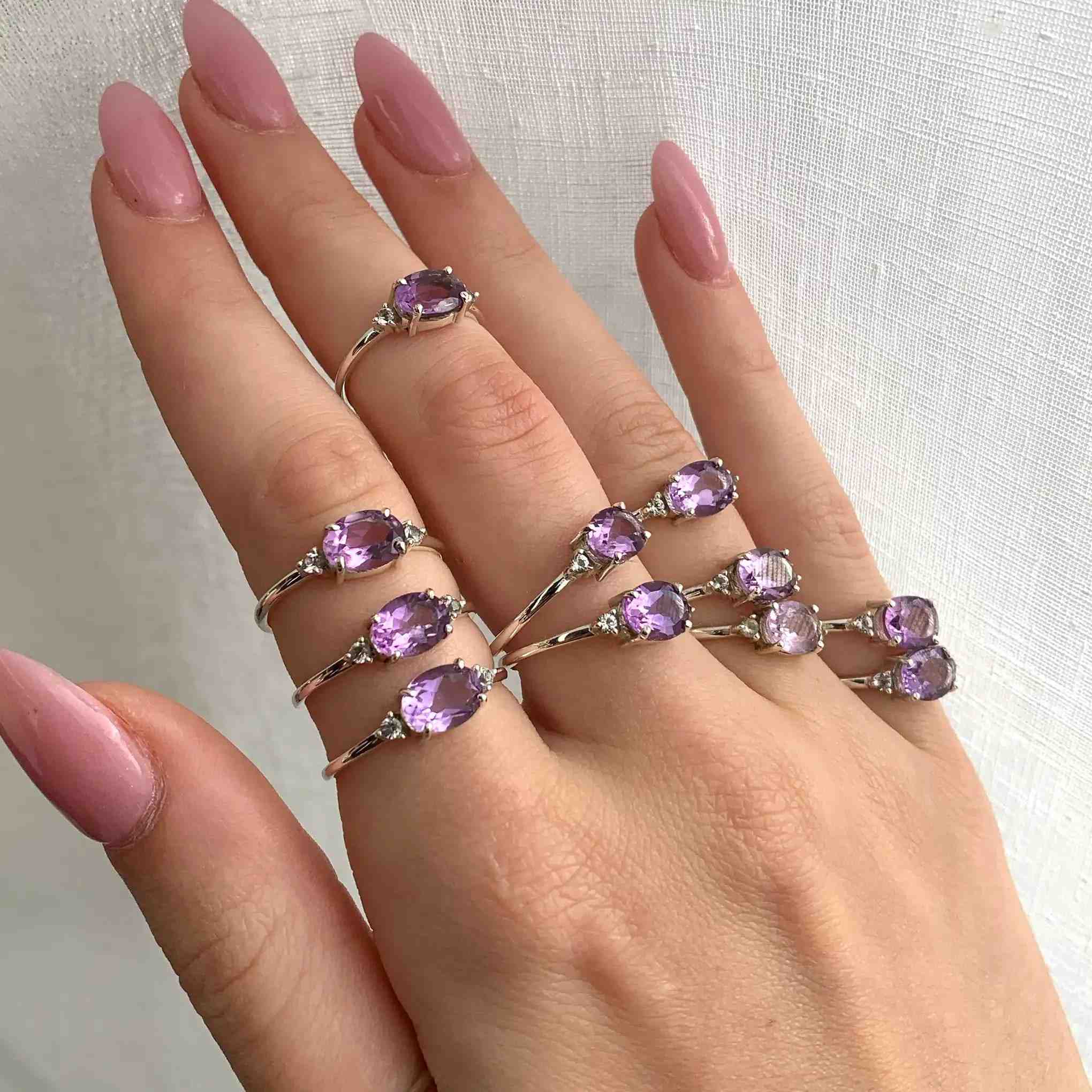 Hand wearing multiple sterling silver rings with natural pink amethyst gemstones 
