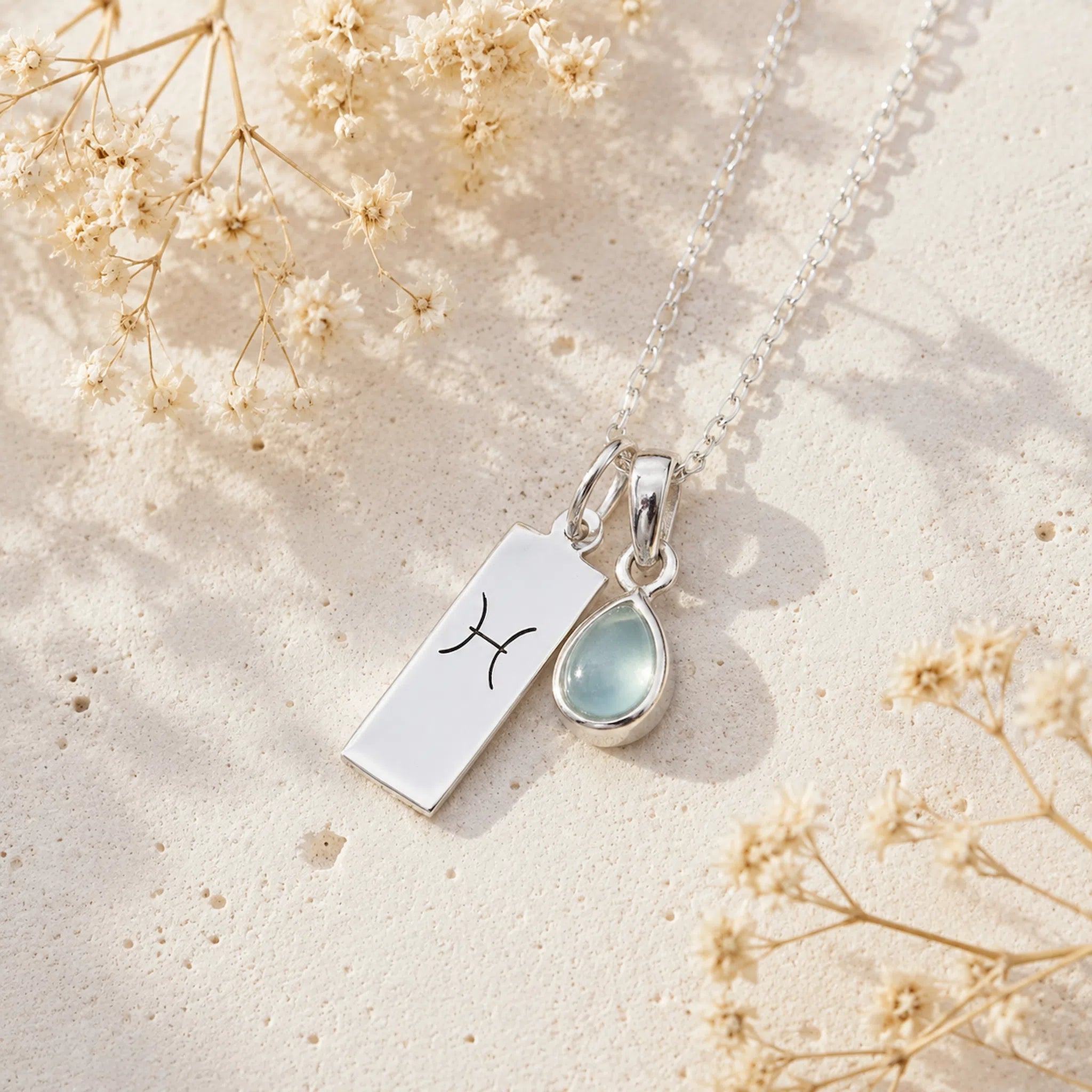 Sterling Silver Necklace with teardrop March Birthstone Natural Aquamarine pendant and a rectangle pendant wth Pisces line glyph on a light background.