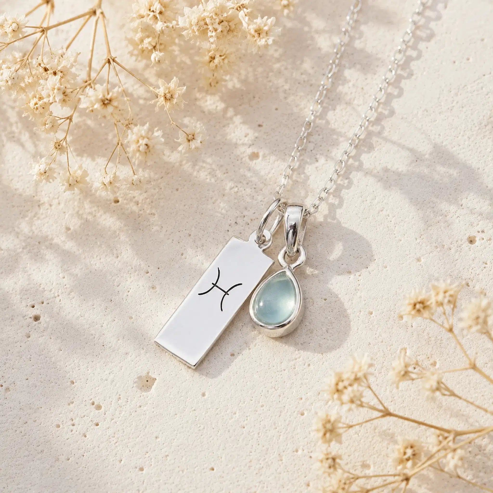 Sterling Silver Necklace with teardrop March Birthstone Natural Aquamarine pendant and a rectangle pendant wth Pisces line glyph on a light background.
