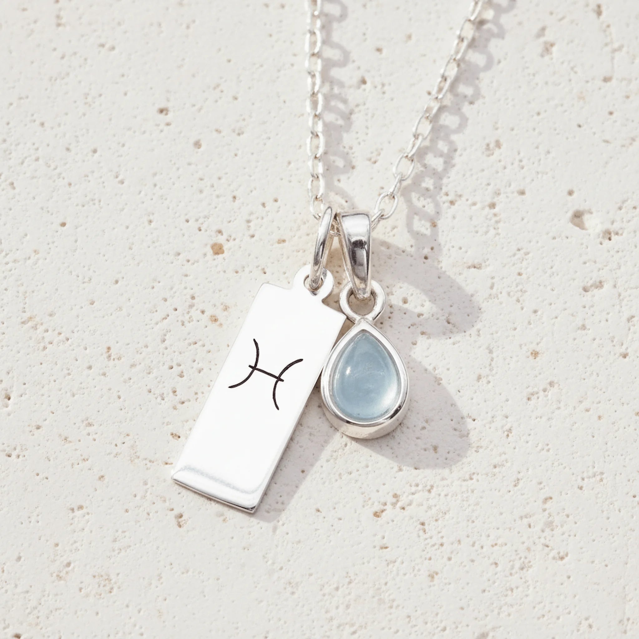 Sterling Silver necklace with a March Birthstone aquamarine pendant and a Pisces Zodiac Star Sign on a white background