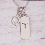 Sterling Silver Q Initial pendant and Aries necklace on a fine silver chain on a light wooden background
