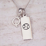 Sterling Silver Q Initial Cancer Zodiac Star Sign Necklace on a fine silver chain against a light wooden background