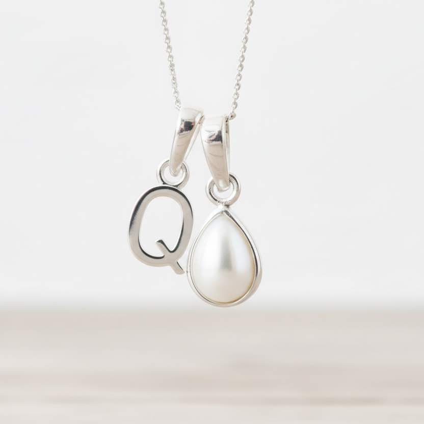 Silver necklace with a Q initial pendant and a teardrop-shaped pearl on a white background