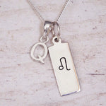 sterling silver initial q leo zodiac star sign pendant necklace against a light wooden background