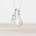 Sterling Silver necklace with 'R' pendant and teardrop-shaped pearl on a white background