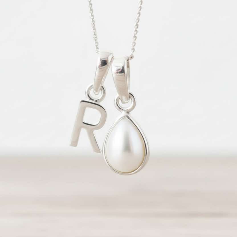 Sterling Silver necklace with 'R' pendant and teardrop-shaped pearl on a white background