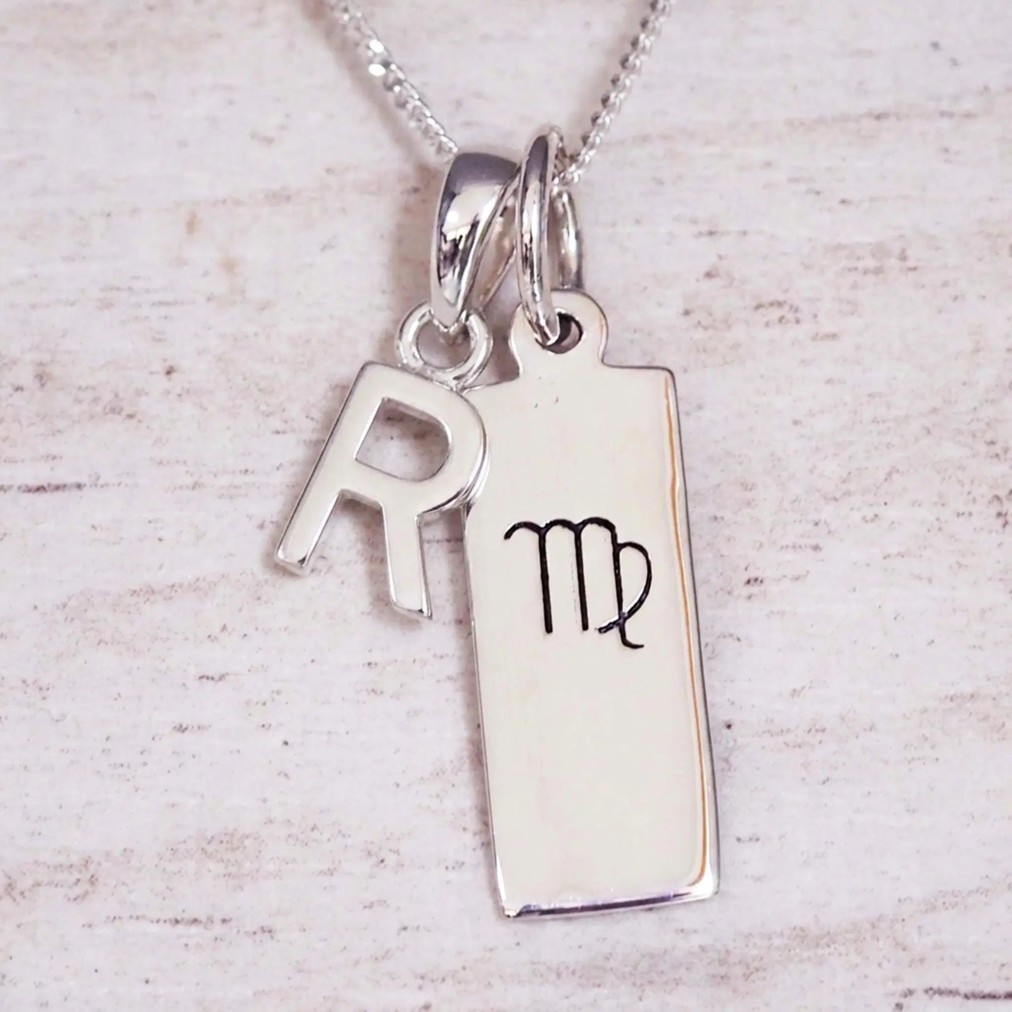 sterling silver initial r virgo zodiac star sign pendant necklace against a light wooden background