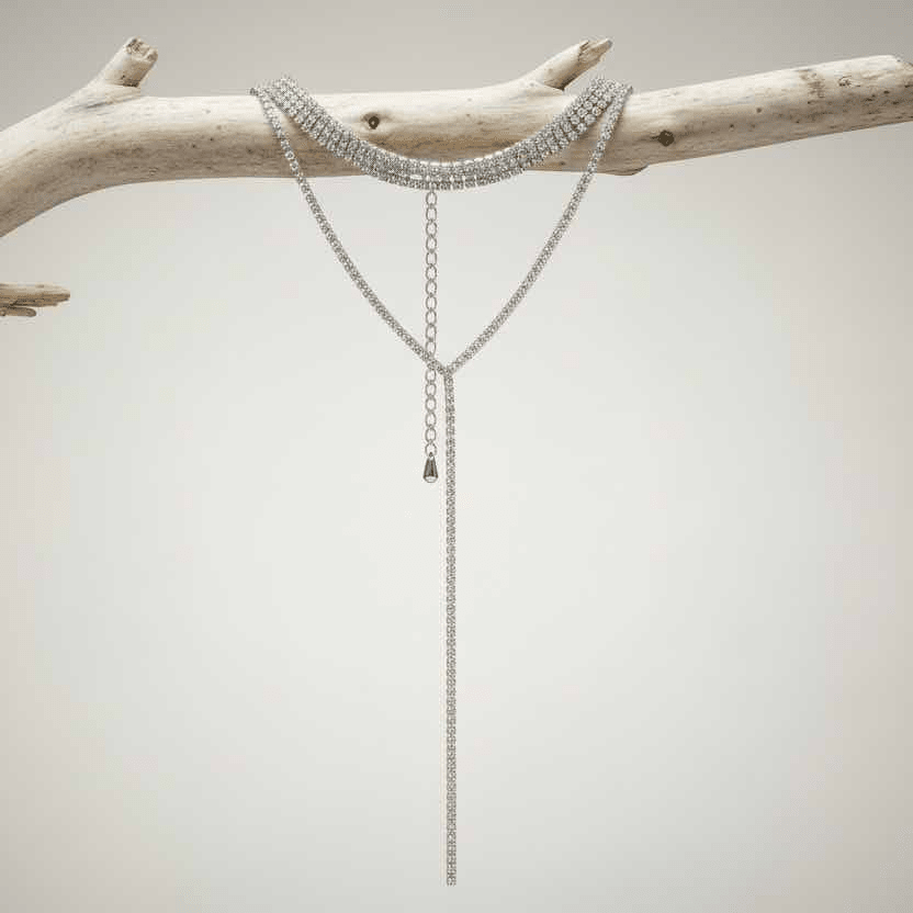 Silver rhinestone chain necklace on a branch against a neutral background