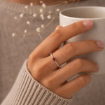Hand holding a white mug with a sterling silver cubic zirconia pave stacking ring featuring a natural red ruby gemstone