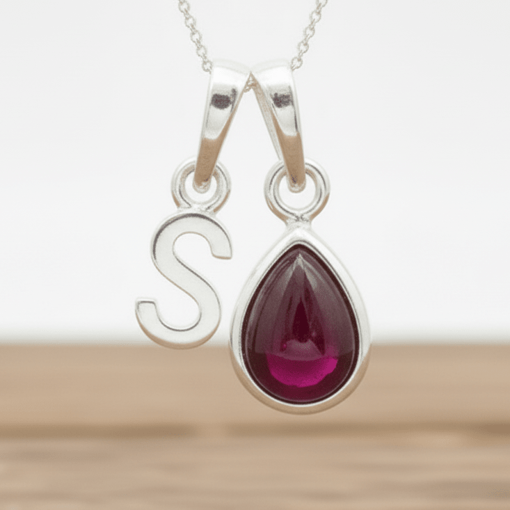 Silver s initial necklace with a teardrop-shaped red ruby gemstone pendant on a white background