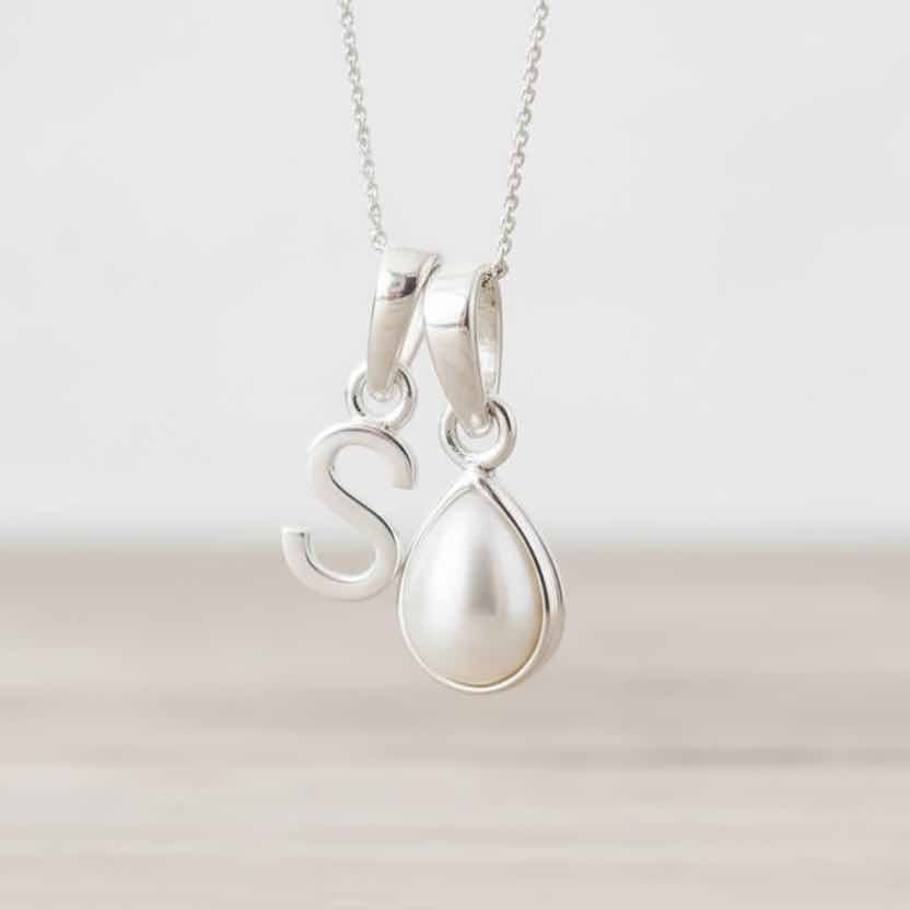 Sterling Silver necklace with a S initial pendant and a teardrop-shaped pearl pendant on a light background