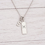sterling silver S initial Pisces Necklace on a fine silver chain against a light wooden background