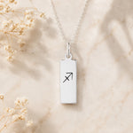 dainty sterling silver fine chain necklace with a rectangle pendant engraved with sagittarius zodiac line glyph symbol hanging.