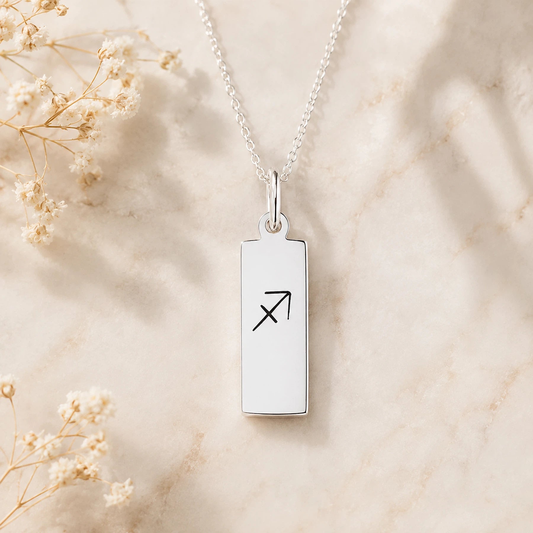 sterling silver sagittarius necklace featuring rectangle pendant engraved with minimalist sagittarius zodiac star sign line glyph symbol suspended from a fine chain