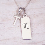 Silver Initial and Scorpio Zodiac Necklace with a letter T pendant and engraved Scorpio bar, flat lay on light wood