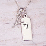 Silver Initial and Scorpio Zodiac Necklace with a letter Y pendant and engraved Scorpio bar, flat lay on light wood