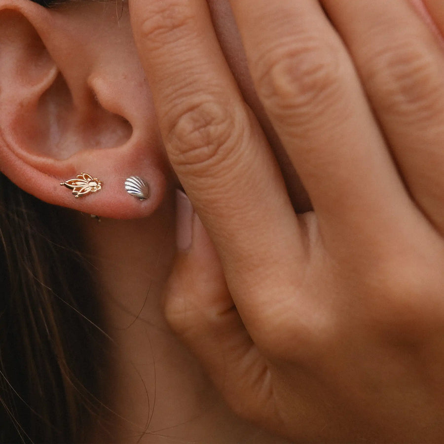 woman wearing gold lotus stud and sterling silver sea shell stud