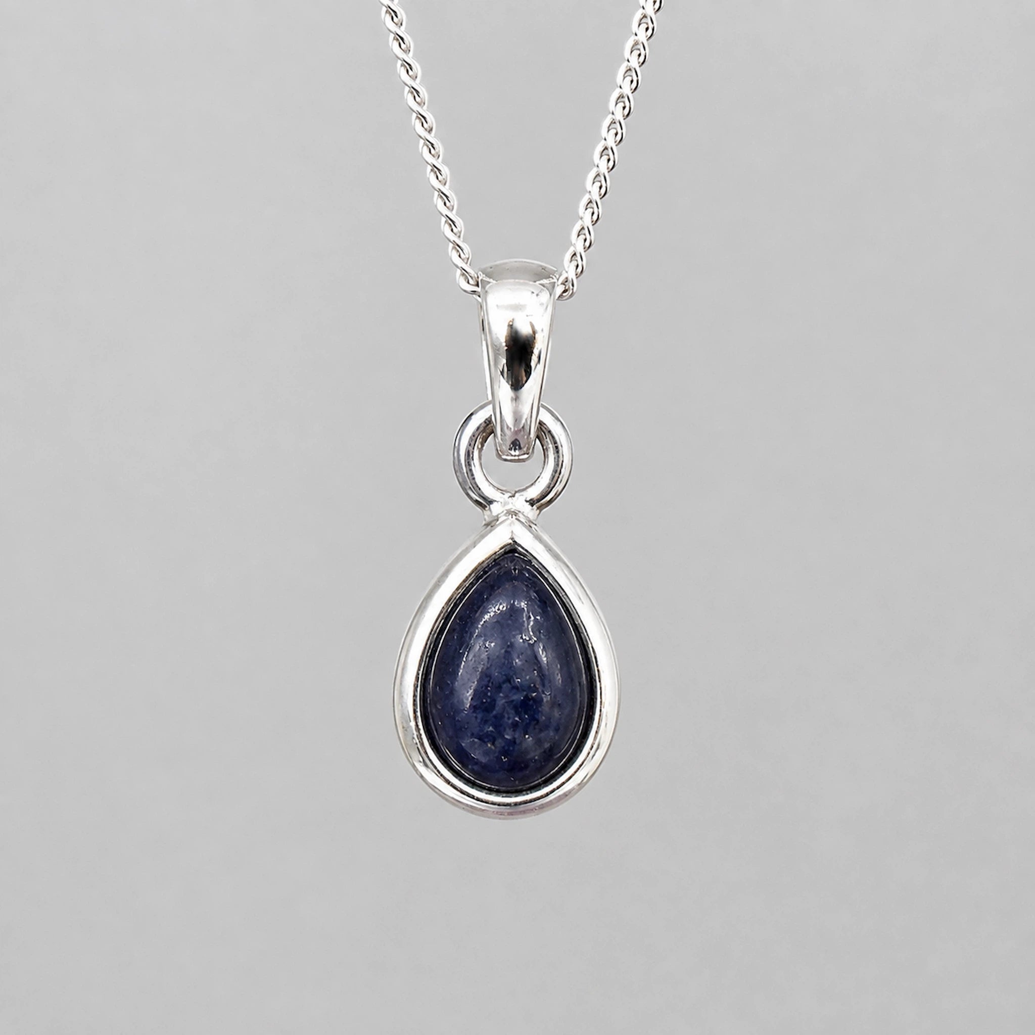 September Birthstone Natural Sapphire Necklace - A silver teardrop pendant necklace featuring a polished dark blue lapis lazuli stone, shown against a neutral gray background.