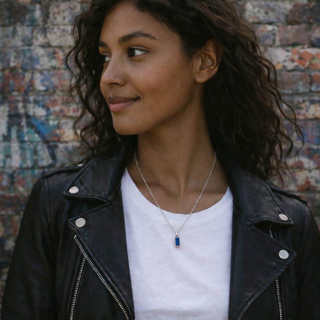 woman with black hair and leather jacket wearing a silver necklace with dark blue crystal pendant