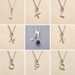 Collection of silver letter pendants J to  on beige backgrounds as initial options for September Birthstone Sapphire Necklace.