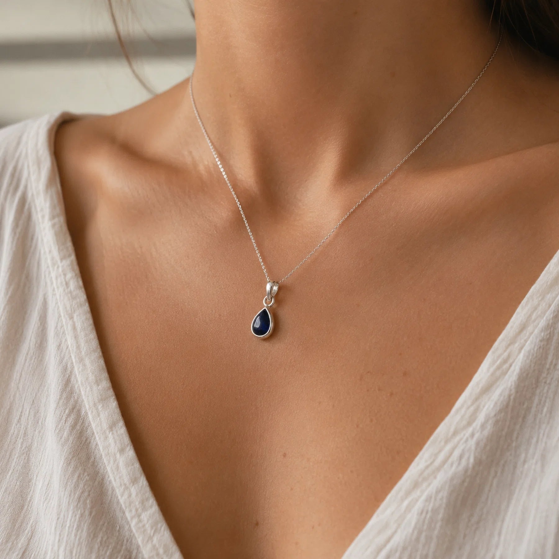 Sterling silver september birthstone necklace with a pear-shaped sapphire gemstone worn 