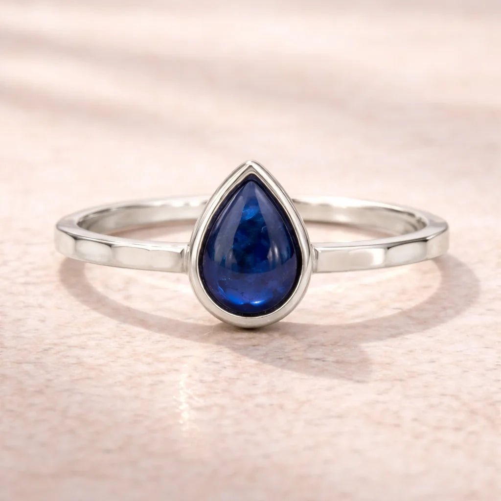 sterling Silver ring with a blue teardrop-shaped natural sapphire gemstone on a light pink background