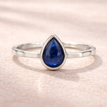 sterling Silver ring with a blue teardrop-shaped natural sapphire gemstone on a light pink background