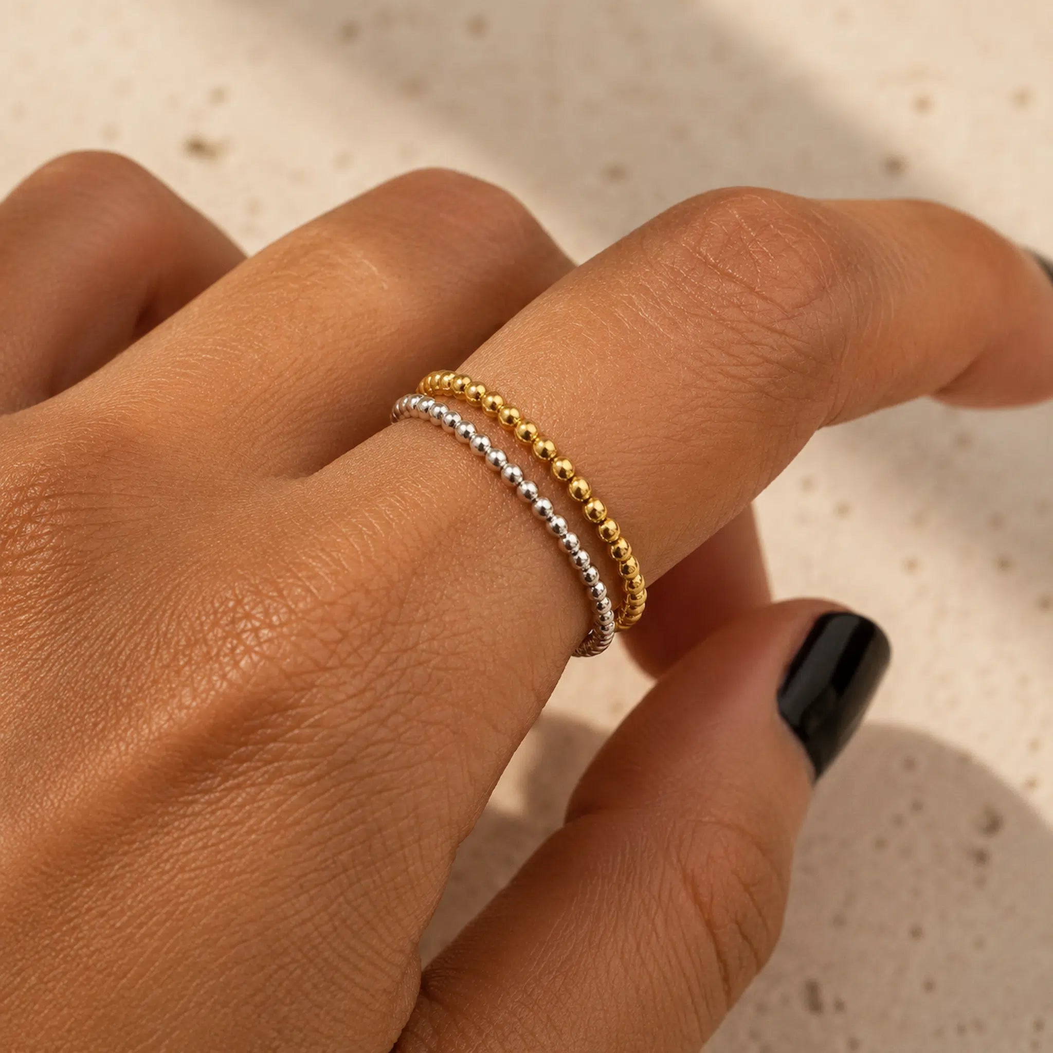 Hand wearing two rings, one is a sterling silver beaded stacker and the other is a gold vermeil stacker ring