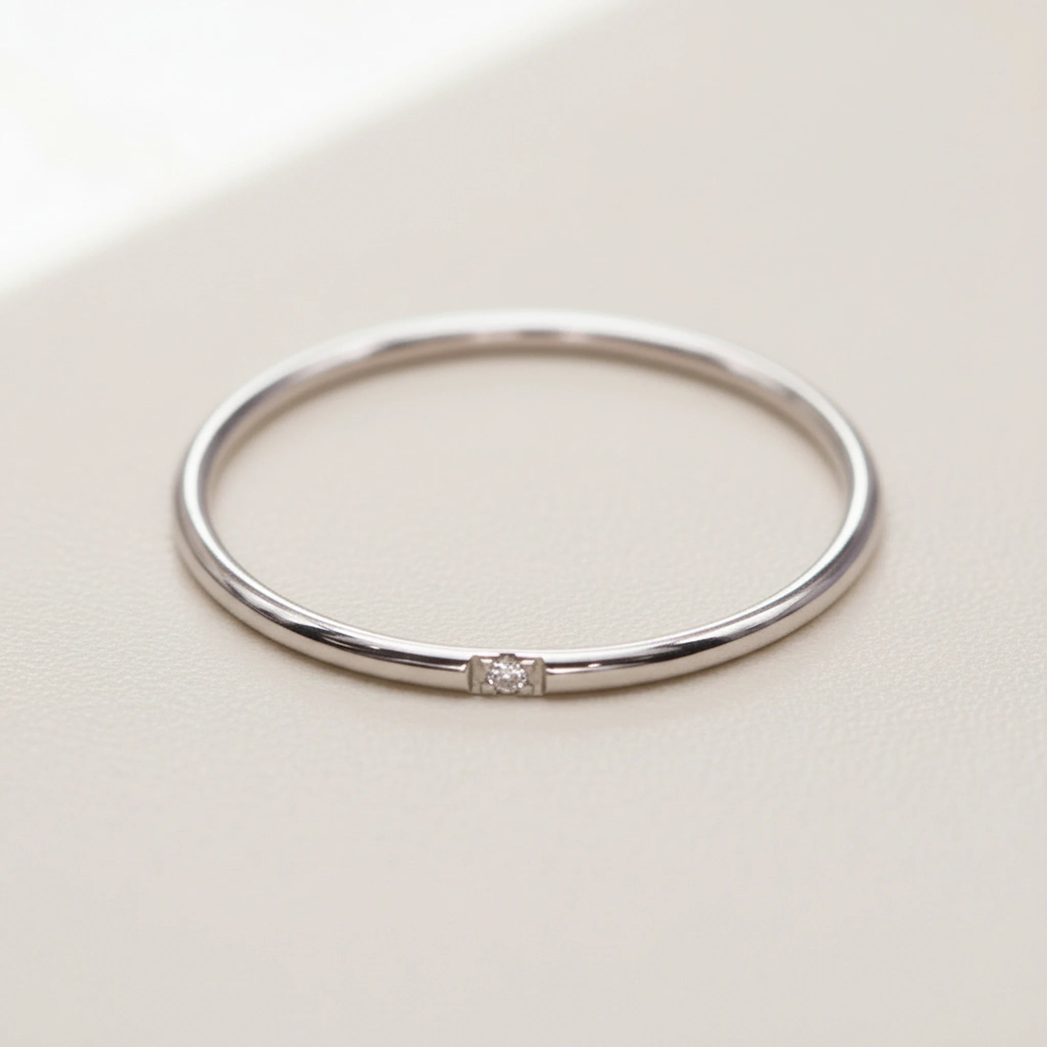 minimalist waterproof silver stacker ring with a dainty cubic zirconia on a white background
