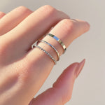 Hand wearing three silver stacker rings with a light background