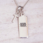 Sterling Silver T Initial and Aquarius Necklace on a fine silver chain against a light wooden background