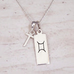 Sterling silver T initial and GeminI Necklace on a fine silver chain on a light wooden background