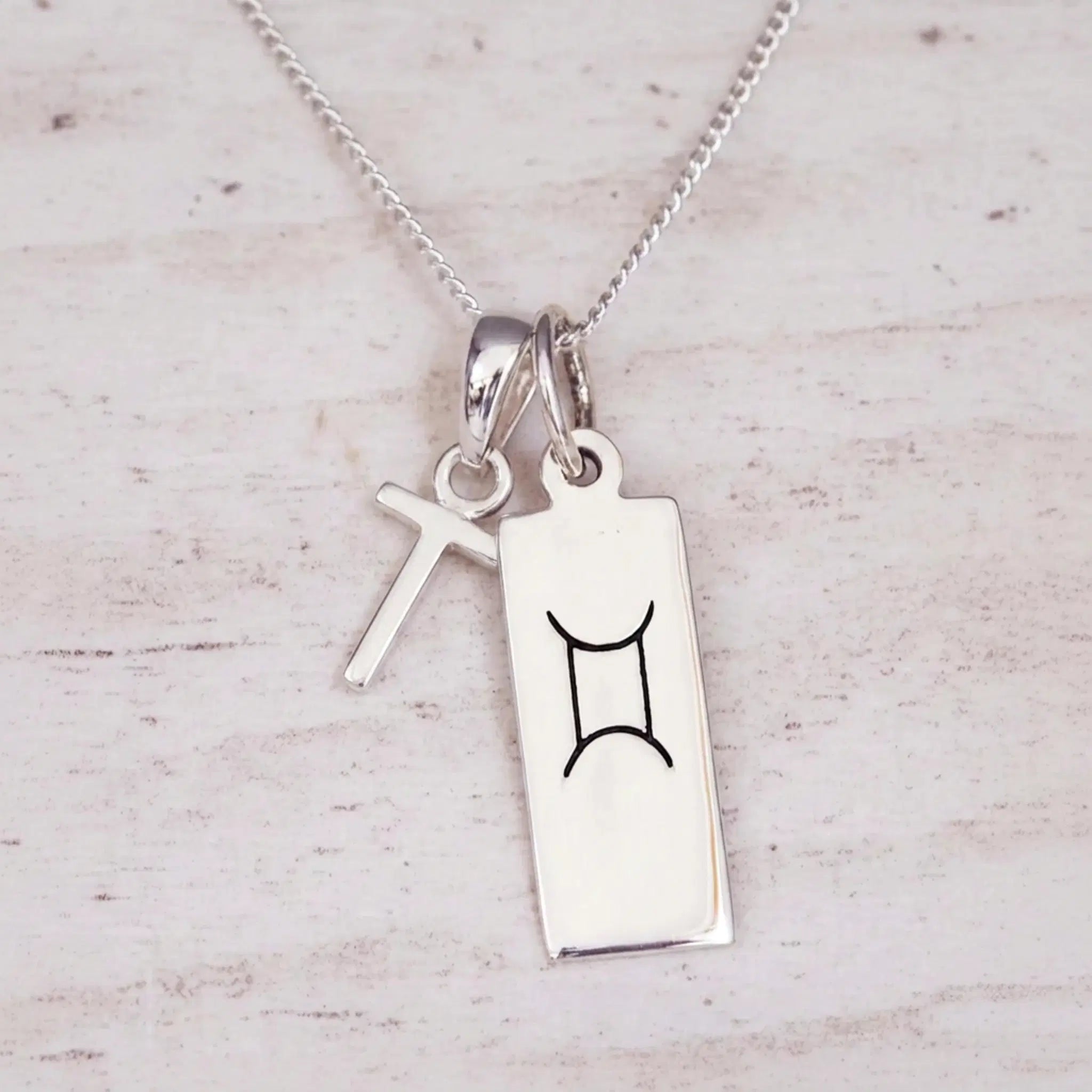 Sterling silver T initial and GeminI Necklace on a fine silver chain on a light wooden background