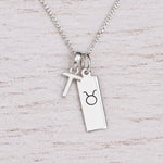 Sterling silver T initial Pendant and Taurus Necklace on a fine silver chain on a light wooden background