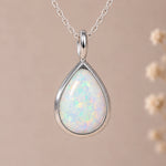 close up of a tear-drop white opal pendant bezel set in sterling silver and hanging from a silver chain