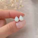 sterling silver stud earrings with teardrop bezel set white opals being held
