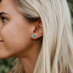 silver turquoise earrings featuring round cabochon bezel set natural turquoise gemstone studs being worn