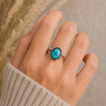 hand wearing a sterling silver oxidised ring with a natural turquoise stone, hand crafted by navajo artisans.