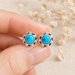 fingers holding a pair of sterling silver turquoise stud earrings