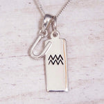 Sterling Silver U Initial and Aquarius Necklace on a fine silver chain against a light wooden background