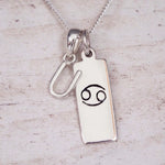 Sterling Silver U Initial Cancer Zodiac Star Sign Necklace on a fine silver chain against a light wooden background