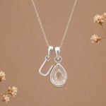 sterling silver initial u april birthstone natural clear quartz pendant necklace against a dark warm beige background