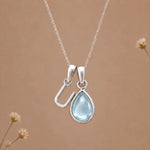 sterling silver initial u march birthstone natural aquamarine pendant necklace against a dark warm beige background